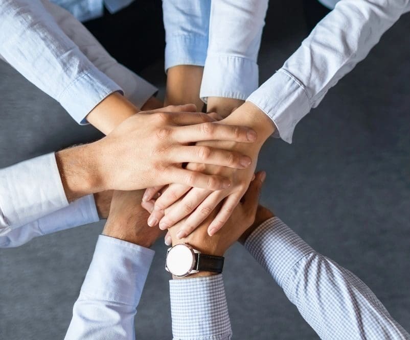 Hands stacked in teamwork gesture.