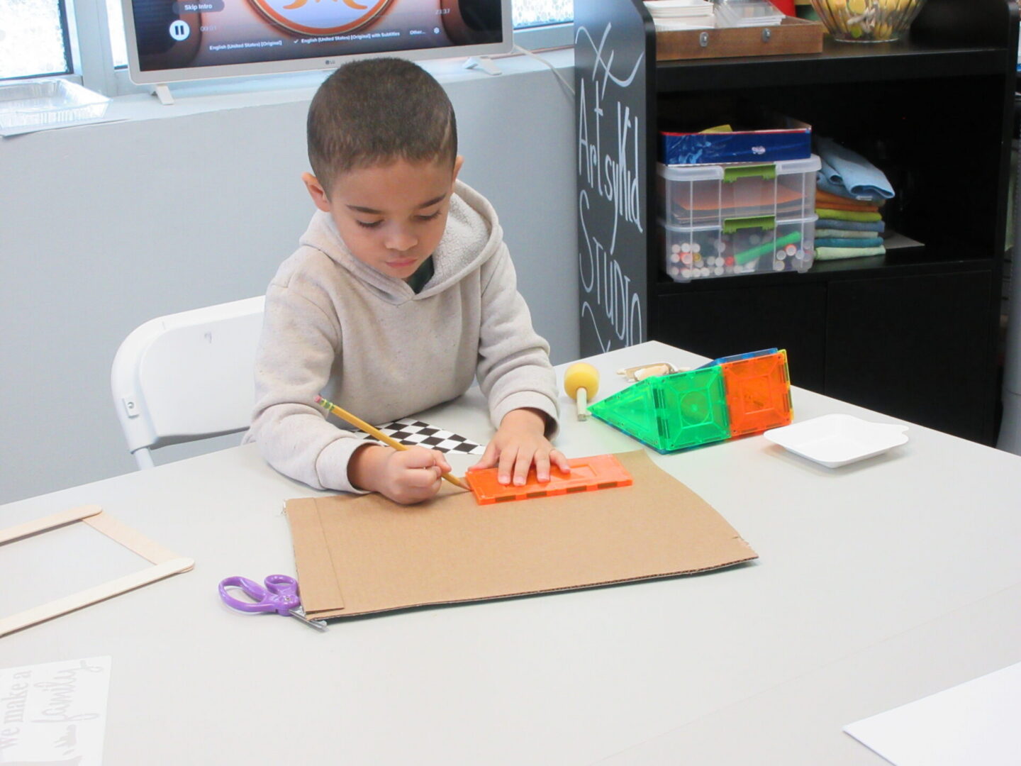 Young child drawing on cardboard at craft table