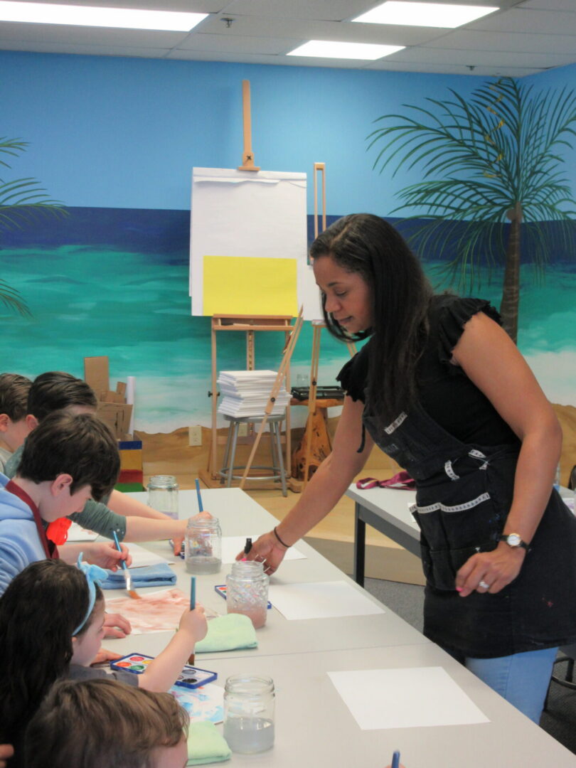 Art instructor guiding children painting at table