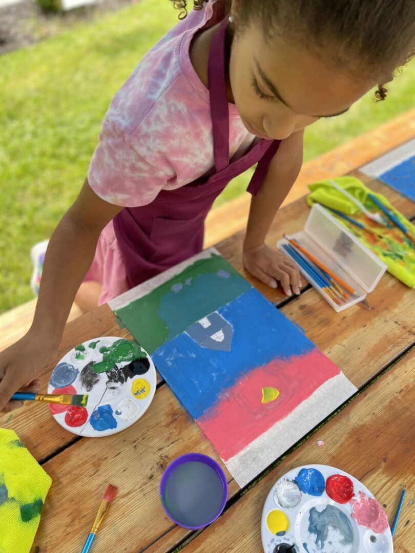 Child painting with colorful paints outdoors