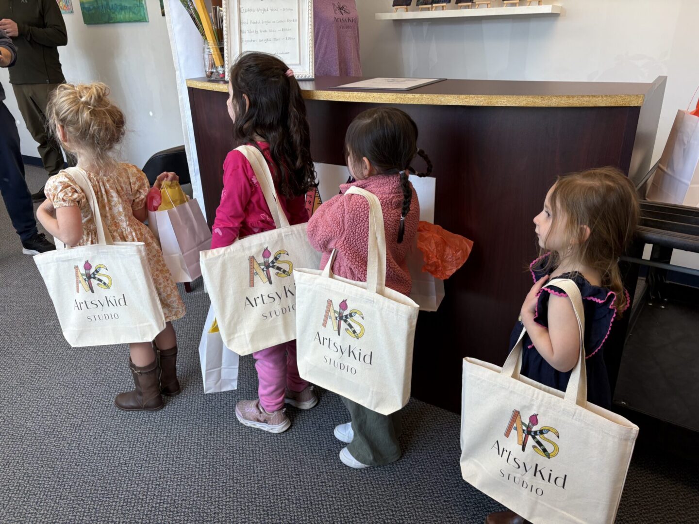 Children with ArtsyKid tote bags at counter