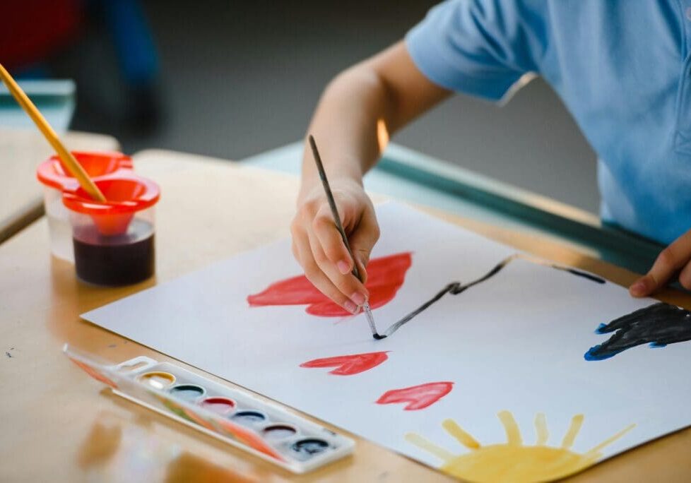 Child painting with watercolors on paper.