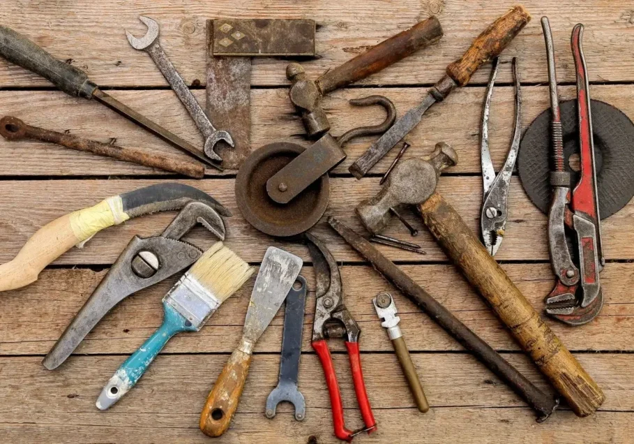 Assorted vintage tools on wooden surface.